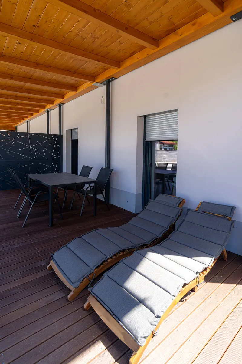 Pokrita zasebna terasa z ležalnikoma, mizo in stoli