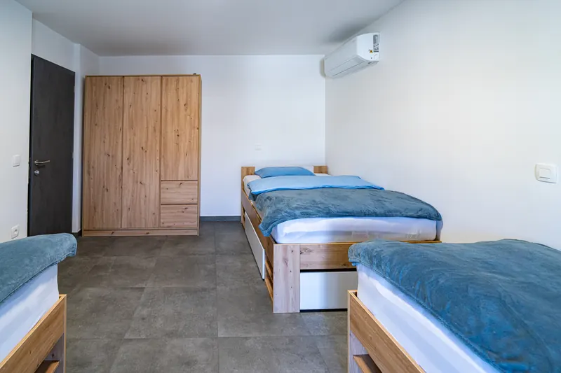 Spalnica z zakonsko in enojnima posteljama, omaro ter klimo
