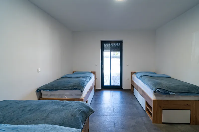 Svetla spalnica s tremi posteljami in izhodom na teraso