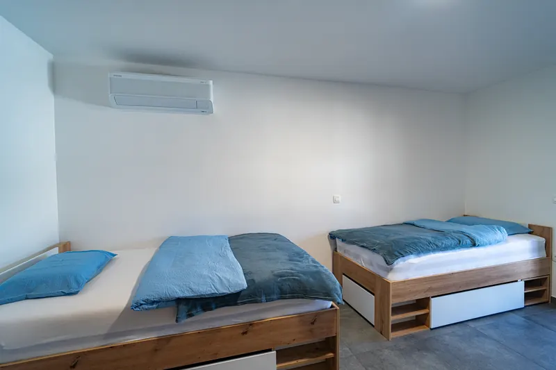 Spalnica z dvema posteljama, klimo in predali za shranjevanje